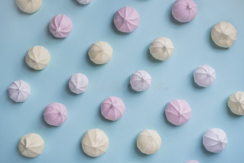 Färgrik matmodell av rosa färg-, guling- och vitmarängar på blå bakgrund arkivbild Färgrik matmodell av rosa färg-, guling- och vitmarängar på blå bakgrund arkivbild