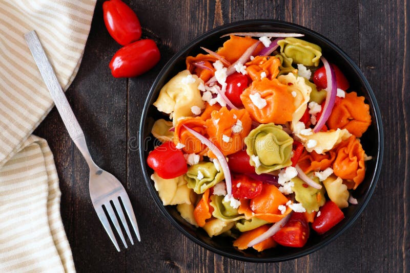 Färgrik tortellinipastasallad, över huvudet plats på mörkt trä arkivfoto Färgrik tortellinipastasallad, över huvudet plats på mörkt trä arkivfoto