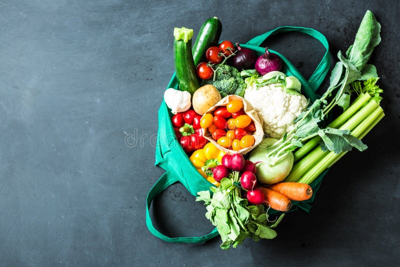 Colorful organic vegetables in green eco shopping bag - captured from above top view, flat lay. Black chalkboard blackboard as background. Layout with free text copy space. Colorful organic vegetables in green eco shopping bag - captured from above top view, flat lay. Black chalkboard blackboard as background. Layout with free text copy space.