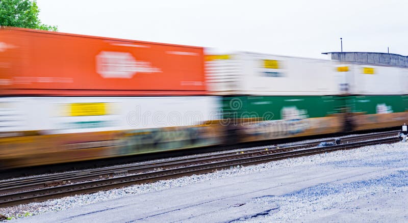A blurry view of a colorful double-stack freight train speeding through a rail yard. A blurry view of a colorful double-stack freight train speeding through a rail yard.