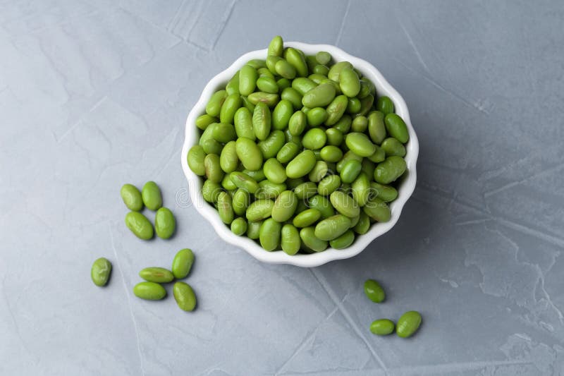 Färska edamame sojabönor i skål på grått texturerat bord, ovanifrån royaltyfri bild