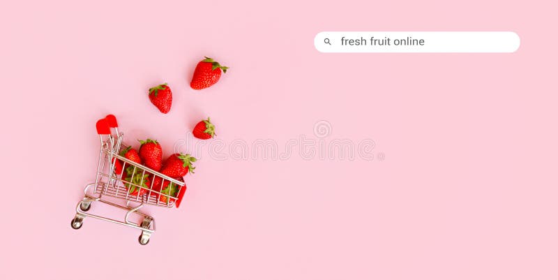 Färska jordgubbar i shoppingvagn på rosa bakgrund. onlineköp och vardagsminimalistiskt koncept. royaltyfri bild