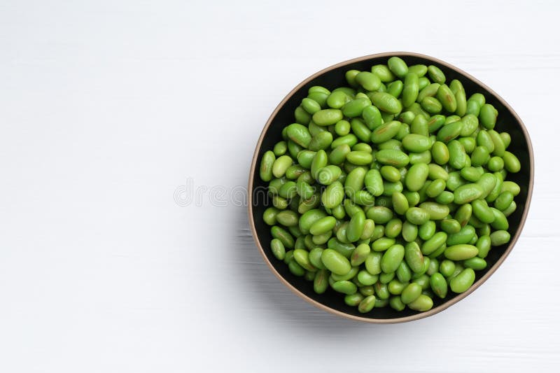 Färska edamame sojabönor i skål på vitt träbord, ovanifrån. Utrymme för text fotografering för bildbyråer