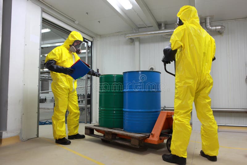 Two specialists in protective uniforms,masks,gloves and boots transport barrels of chemicals on forklift in factory. Two specialists in protective uniforms,masks,gloves and boots transport barrels of chemicals on forklift in factory