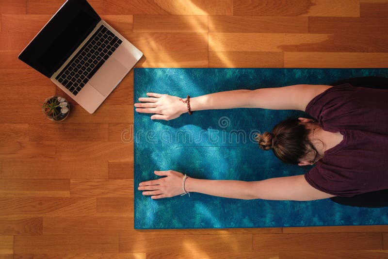 A female stretching over a mat during online yoga class. A female stretching over a mat during online yoga class