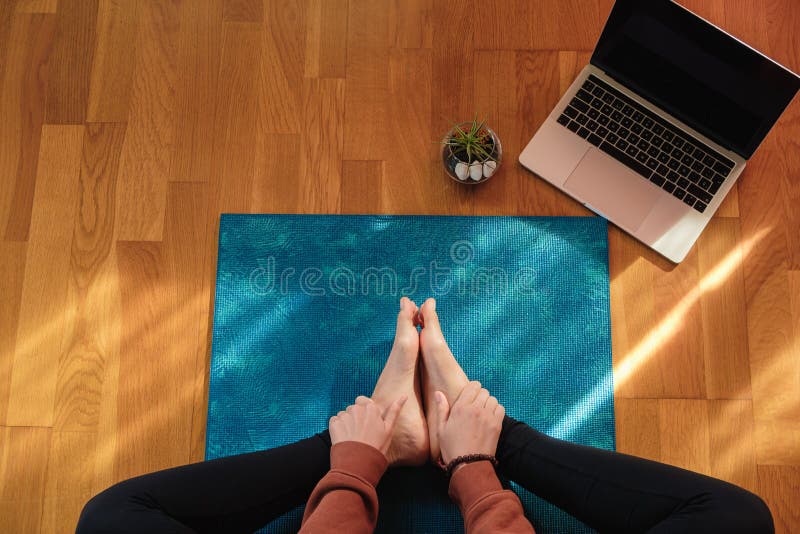 A female stretching over a mat during online yoga class. A female stretching over a mat during online yoga class