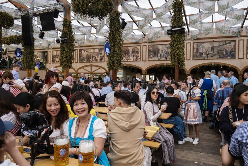 Munich, Germany - October 1, 2023. People relaxing inside the beer tent at Oktoberfest 2023, the world-famous beer festival in the Bavarian culture called d' Wiesn, in Munich, Deutschland. Munich, Germany - October 1, 2023. People relaxing inside the beer tent at Oktoberfest 2023, the world-famous beer festival in the Bavarian culture called d' Wiesn, in Munich, Deutschland.