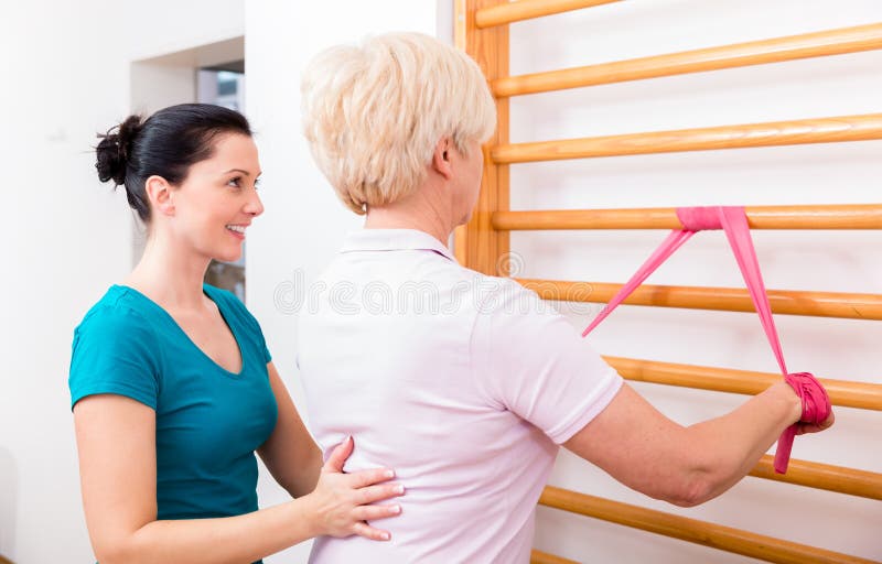Físico mulher idosa de ajuda durante o exercício com faixa a do poder imagens de stock royalty free Físico mulher idosa de ajuda durante o exercício com faixa a do poder imagens de stock royalty free