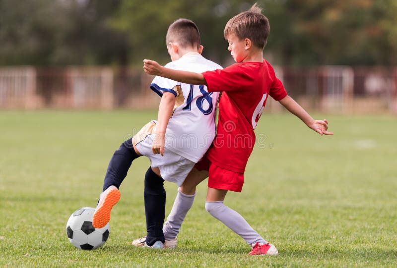 Fósforo de futebol dos jogadores das jovens crianças no campo de futebol imagens de stock royalty free Fósforo de futebol dos jogadores das jovens crianças no campo de futebol imagens de stock royalty free