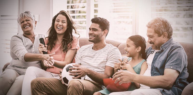 Fósforo de futebol de observação da família feliz da multi-geração na televisão na sala de visitas imagens de stock Fósforo de futebol de observação da família feliz da multi-geração na televisão na sala de visitas imagens de stock