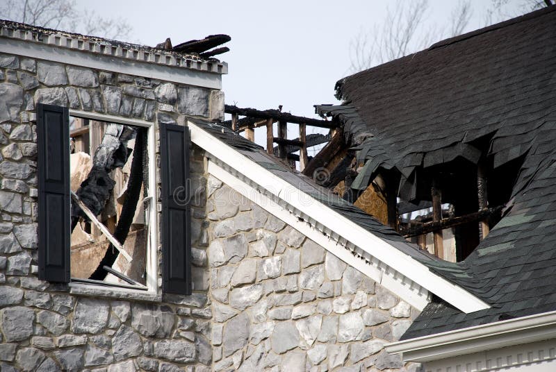 What remains of a luxury home with a stone facade. The roof and attic are gone and the side of the house is charred. What remains of a luxury home with a stone facade. The roof and attic are gone and the side of the house is charred.