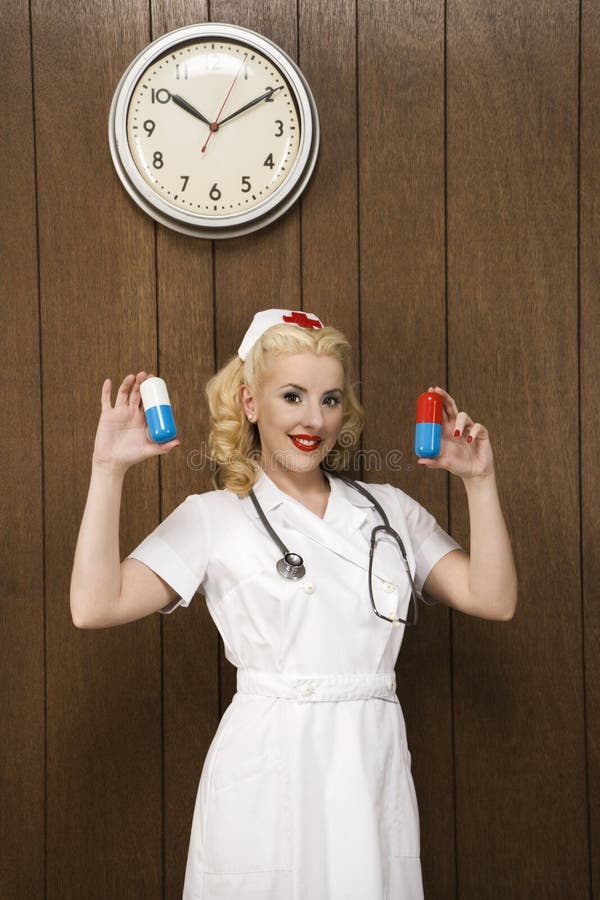 för holdingsjuksköterska för kvinnlig retro likformig för jätte- pills royaltyfri fotografi för holdingsjuksköterska för kvinnlig retro likformig för jätte- pills royaltyfri fotografi