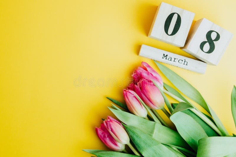 8 March Happy Women`s Day concept. With wooden block calendar and pink tulips on yellow background. 8 March Happy Women`s Day concept. With wooden block calendar and pink tulips on yellow background.