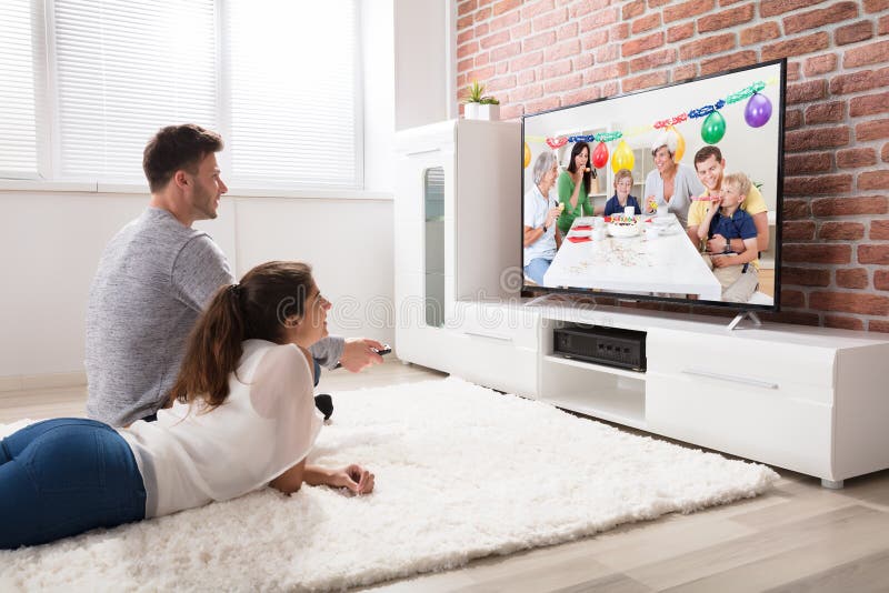 För partiberöm för par hållande ögonen på video på television arkivbild För partiberöm för par hållande ögonen på video på television arkivbild