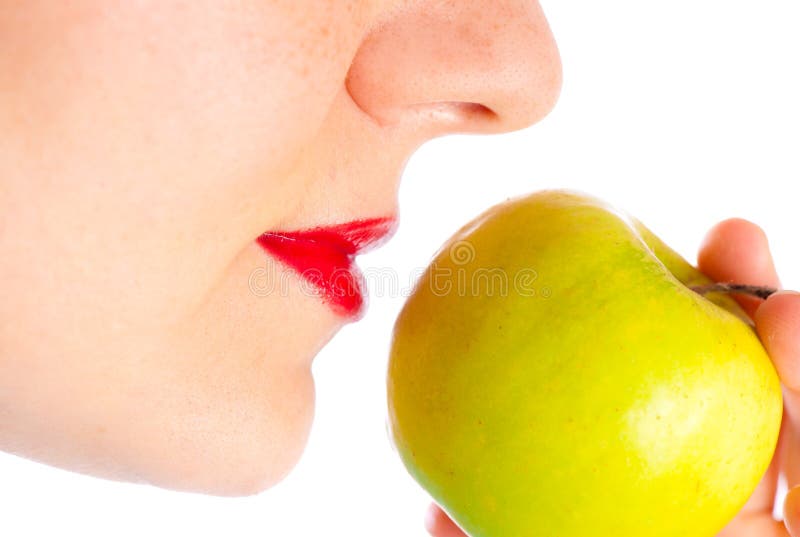 Part of the profile of a girl wearing red lipstick, holding a green apple in front of them. Part of the profile of a girl wearing red lipstick, holding a green apple in front of them