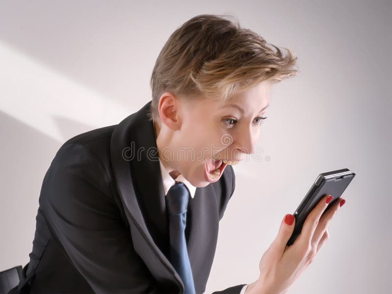 Annoyed business woman in black suit screaming in anger into smart phone. Annoyed business woman in black suit screaming in anger into smart phone.