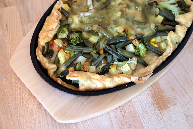Förberedd aptitretande vegetarisk pizza med grönsaker och ost i bästa sikt för svart panna för järn oval royaltyfri fotografi