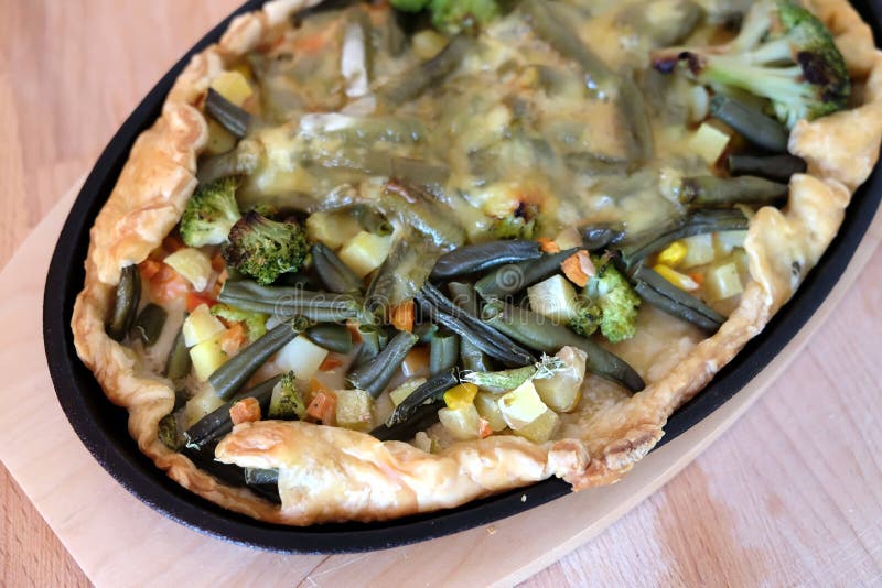 Förberedd aptitretande vegetarisk pizza med grönsaker och ost i bästa sikt för svart panna för järn oval royaltyfri foto
