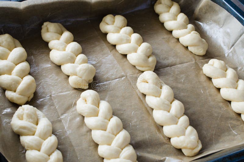 Förberedelseprocess - rå unbaked bullar Hemlagade traditionella råttsvansbullar på att baka papper arkivbilder Förberedelseprocess - rå unbaked bullar Hemlagade traditionella råttsvansbullar på att baka papper arkivbilder