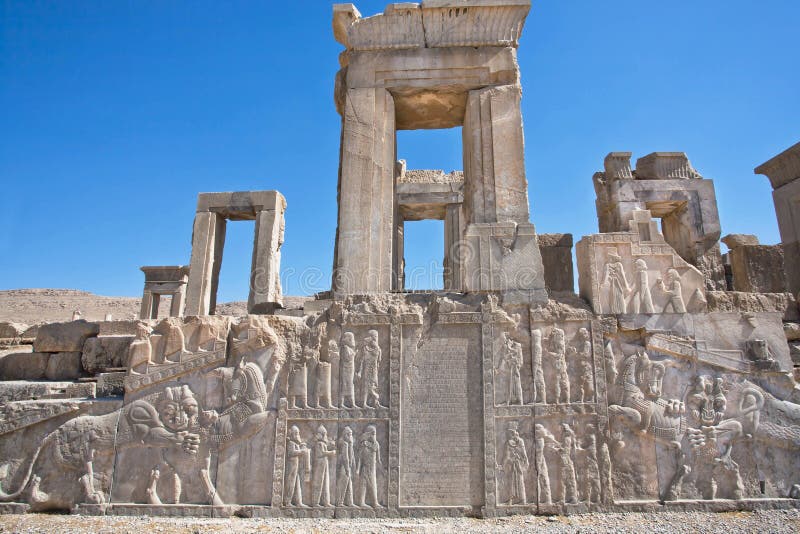 Ruins of ancient palace with columns and bas-relief with symbols of Zoroastrians - fighting bull and a lion, Persepolis, modern Iran. Persepolis was a capital of the Achaemenid Empire (550 - 330 BC). Ruins of ancient palace with columns and bas-relief with symbols of Zoroastrians - fighting bull and a lion, Persepolis, modern Iran. Persepolis was a capital of the Achaemenid Empire (550 - 330 BC)