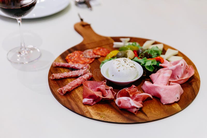 Förkylning rökte köttplattan med prosciuttoen, salami, bacon, fläskkotletter, ost och oliv på träplattan med rött vin fotografering för bildbyråer Förkylning rökte köttplattan med prosciuttoen, salami, bacon, fläskkotletter, ost och oliv på träplattan med rött vin fotografering för bildbyråer