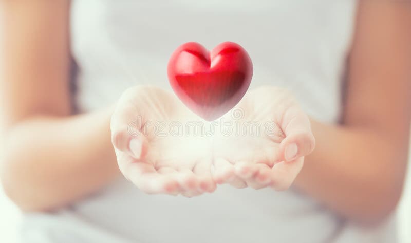 Försiktiga kvinnors händer och röda hjärta som glöder i hans händer Valentinmoderdag och välgörenhetbegrepp