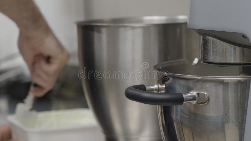 Försluta en professionell bagare med spatel och en planetblandare för att bereda ingredienser för gräddning i ett kök royaltyfria bilder