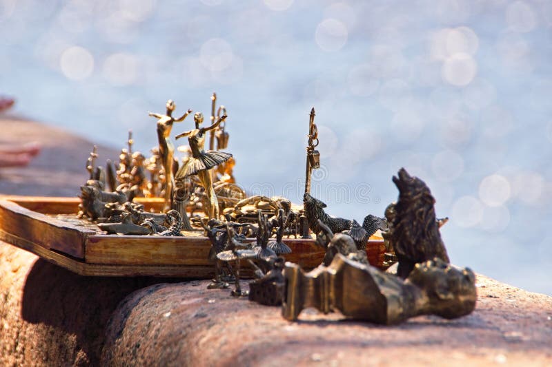 Interesting bronze figurines in vintage classical style depicting people and animals, on the granite parapet of the river embankment, handmade souvenirs in the city center, attractive toys, skillful craft work, semi-blurred background, sunlight, summer. Interesting bronze figurines in vintage classical style depicting people and animals, on the granite parapet of the river embankment, handmade souvenirs in the city center, attractive toys, skillful craft work, semi-blurred background, sunlight, summer.