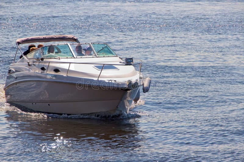 A fast boat with smooth contours on the calm water of a wide river, a vehicle, recreation and entertainment, people on a boat, a sunny day, summer. A fast boat with smooth contours on the calm water of a wide river, a vehicle, recreation and entertainment, people on a boat, a sunny day, summer.