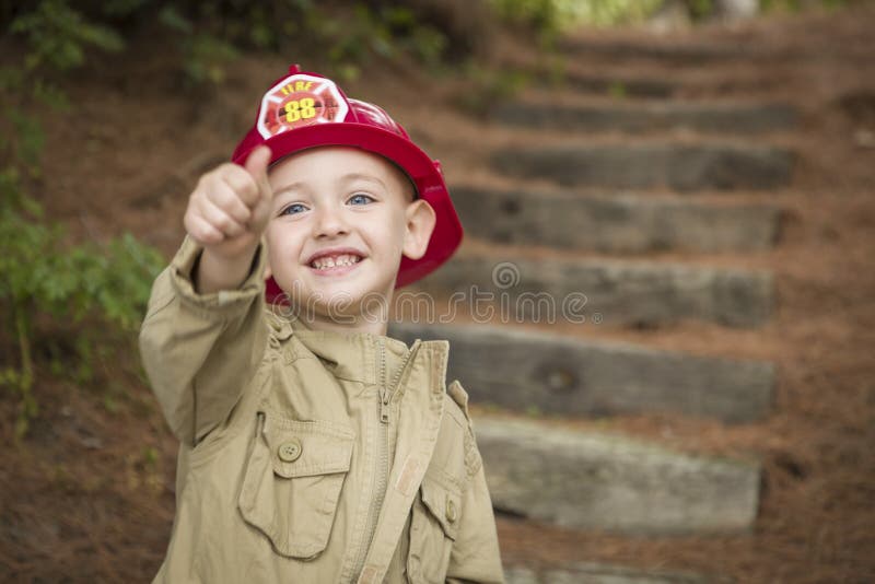 Förtjusande barnpojke med att leka för brandmanhatt royaltyfri foto Förtjusande barnpojke med att leka för brandmanhatt royaltyfri foto