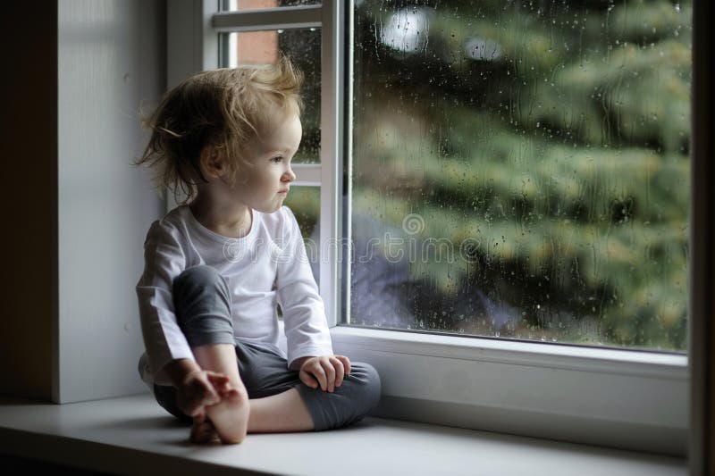 Förtjusande flicka som ser raindropslitet barn royaltyfria foton