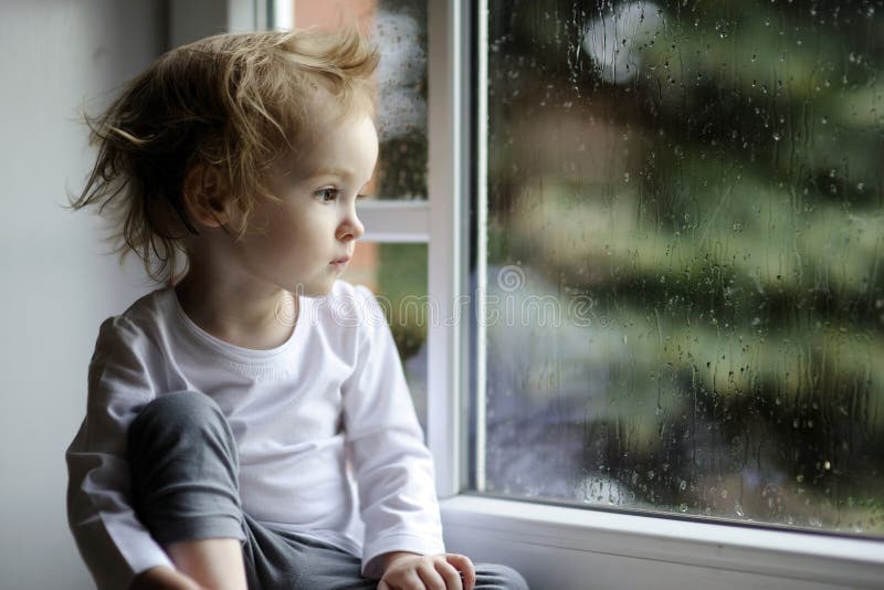 Förtjusande flicka som ser raindropslitet barn royaltyfri bild