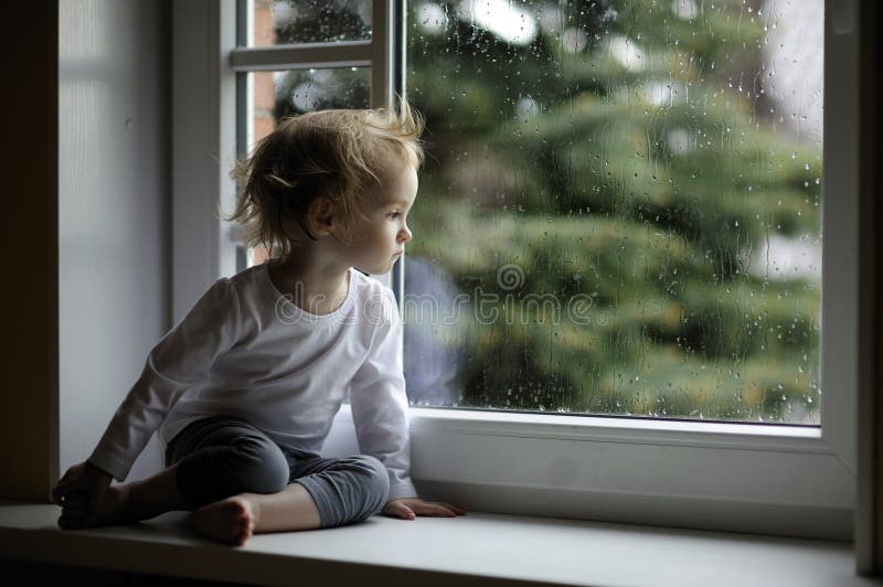 Förtjusande flicka som ser raindropslitet barn fotografering för bildbyråer