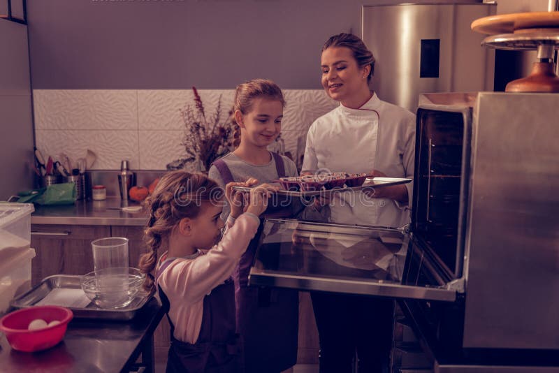Förtjust gullig flicka som rymmer ett magasin med muffin arkivbild Förtjust gullig flicka som rymmer ett magasin med muffin arkivbild