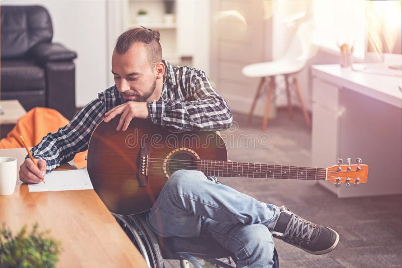 Förtjust stilfull manbenägenhet på hans gitarr arkivbild Förtjust stilfull manbenägenhet på hans gitarr arkivbild