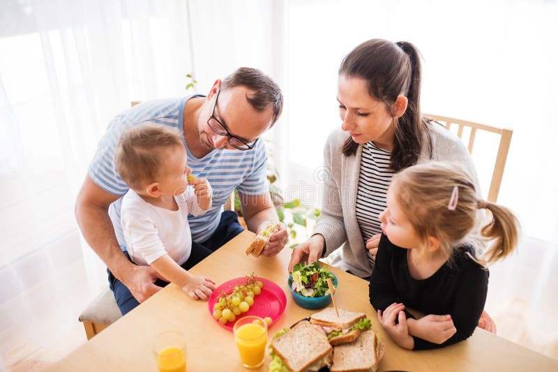 Föräldrar med två barn som äter en smakrik frisk frukost i köket. lycklig familjestund. royaltyfria bilder