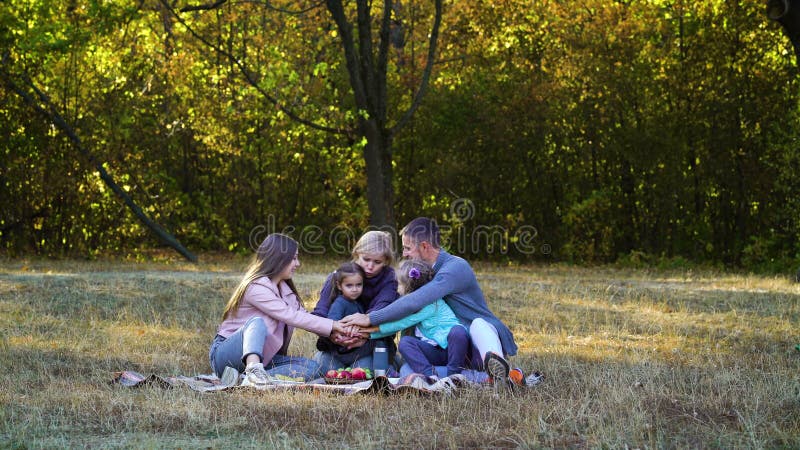 Föräldrar och barn som går i händerna på picknicker