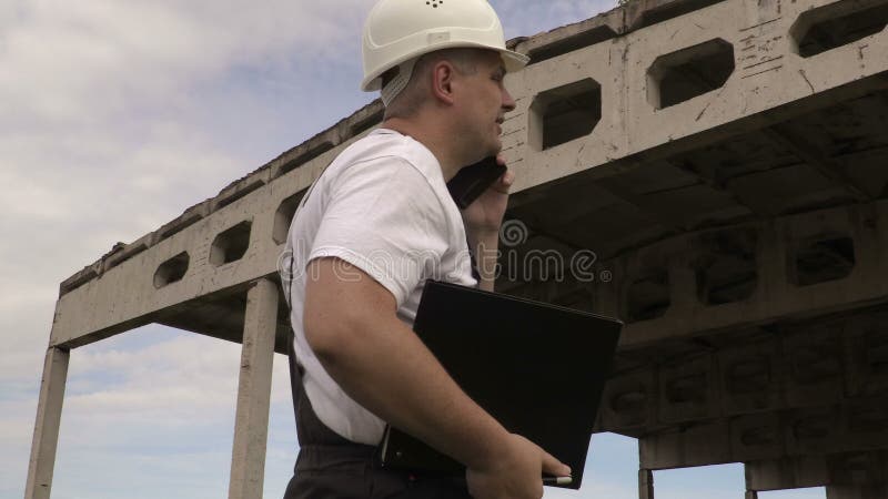 Führen Sie die Unterhaltung am intelligenten Telefon nahe unfertigem Gebäude aus stock video
