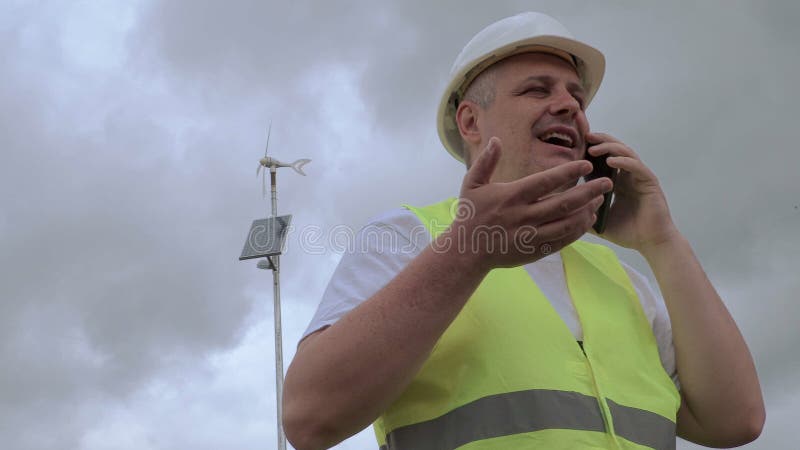 Führen Sie die Unterhaltung am intelligenten Telefon nahe Windgenerator mit Sonnenkollektor aus stock footage