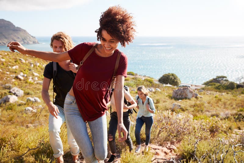 Führende Freunde der tausendjährigen Afroamerikanerfrau auf einer Wanderung ansteigend durch die Küste, Abschluss oben stockbilder