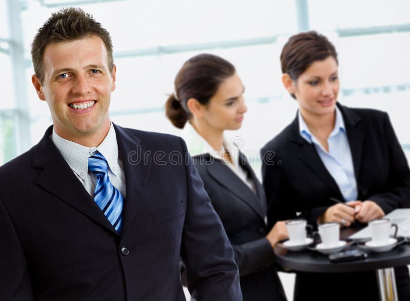 Businessman leading team of business people working in background. Businessman leading team of business people working in background.