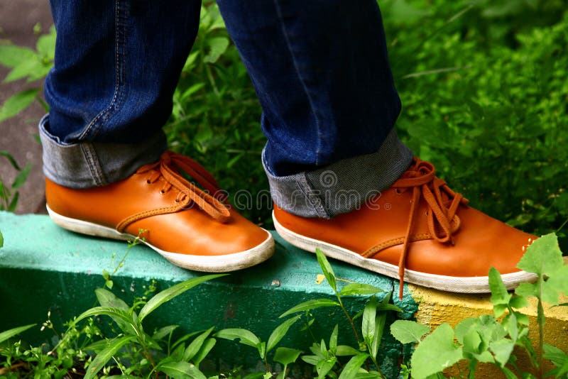 Füße mit orange bequemen Schuhen gehen auf Grenze in der Stadtstraße lizenzfreies stockbild Füße mit orange bequemen Schuhen gehen auf Grenze in der Stadtstraße lizenzfreies stockbild