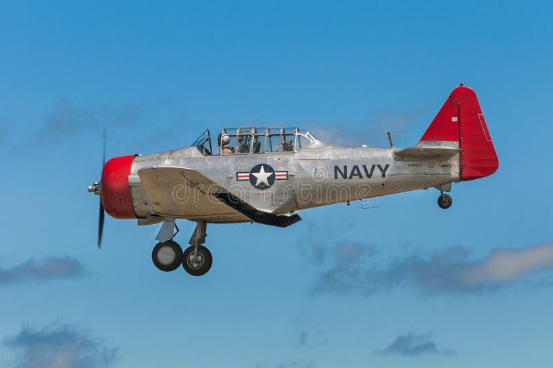 EDEN PRAIRIE, MN - JULY 16, 2016: AT-6G Texan airplane flies by with landing gear down at air show. The AT-6 Texan was primarily used as trainer aircraft during and after World War II. EDEN PRAIRIE, MN - JULY 16, 2016: AT-6G Texan airplane flies by with landing gear down at air show. The AT-6 Texan was primarily used as trainer aircraft during and after World War II.