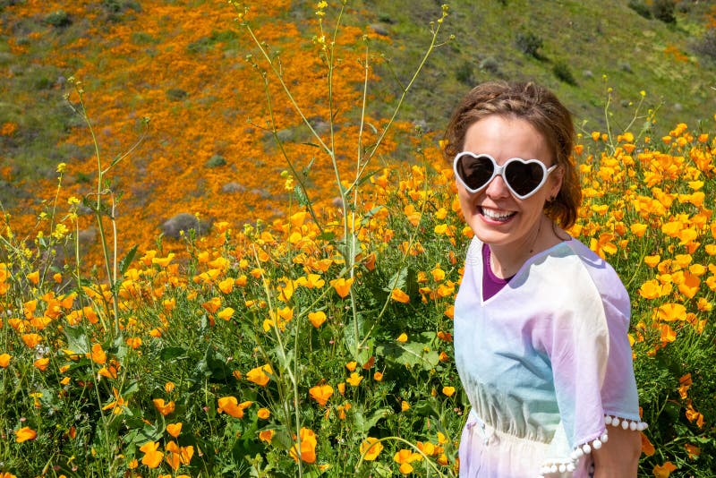 Gafas de sol hermosas del corazón de la mujer que llevan joven y un caftán en colores pastel en un campo de la amapola durante la imágenes de archivo libres de regalías Gafas de sol hermosas del corazón de la mujer que llevan joven y un caftán en colores pastel en un campo de la amapola durante la imágenes de archivo libres de regalías