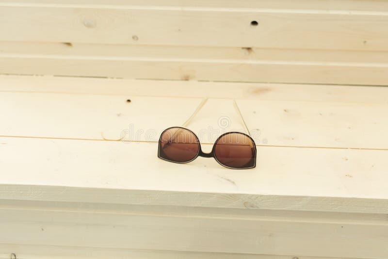Gafas de sol marrones de la moda que mienten en la tabla de madera fotos de archivo Gafas de sol marrones de la moda que mienten en la tabla de madera fotos de archivo