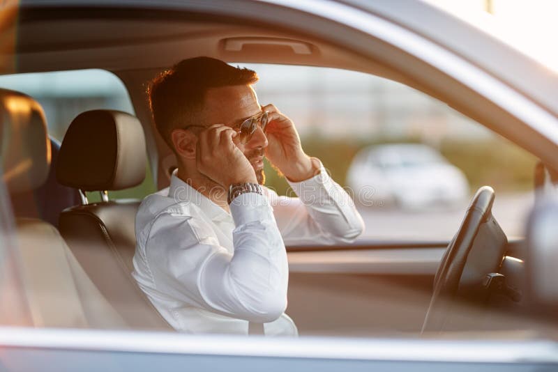 Gafas de sol que llevan del hombre de negocios mientras que conduce el coche imágenes de archivo libres de regalías