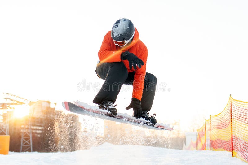 Gai mec en habit de ski orange sauts sur snowboard dans les montagnes à l'hôtel homme en casque de veste et lunettes fait photos libres de droits