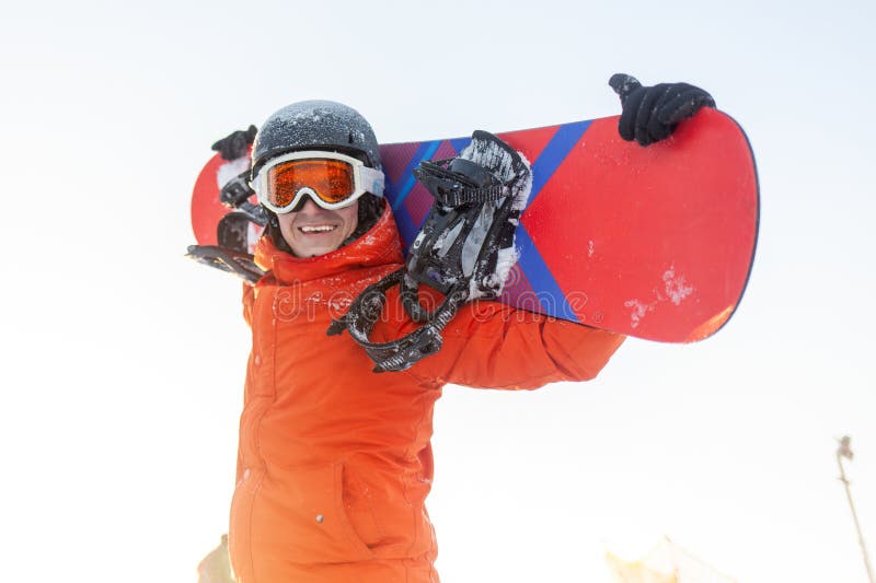 Gai mec en vêtements de ski tient snowboard et sourit à la station image libre de droits