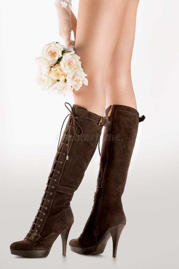 A closeup view of high fashioned leather boots worn by a woman with long legs and holding a bouquet of roses. A closeup view of high fashioned leather boots worn by a woman with long legs and holding a bouquet of roses.
