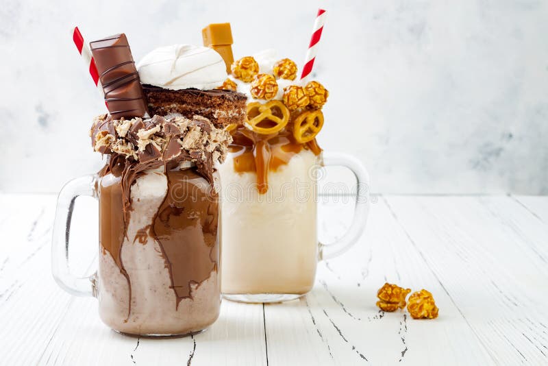 Galen freakshake för karamell och för choklad, milkshakar med brezeldillandear, popcorn, marshmallow, glass och piskad kräm arkivbilder Galen freakshake för karamell och för choklad, milkshakar med brezeldillandear, popcorn, marshmallow, glass och piskad kräm arkivbilder